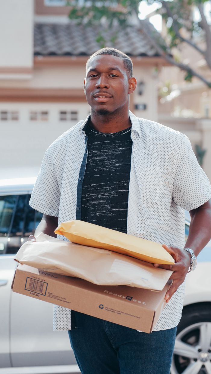 A deliveryman carrying packages outside, showcasing modern online shopping convenience.